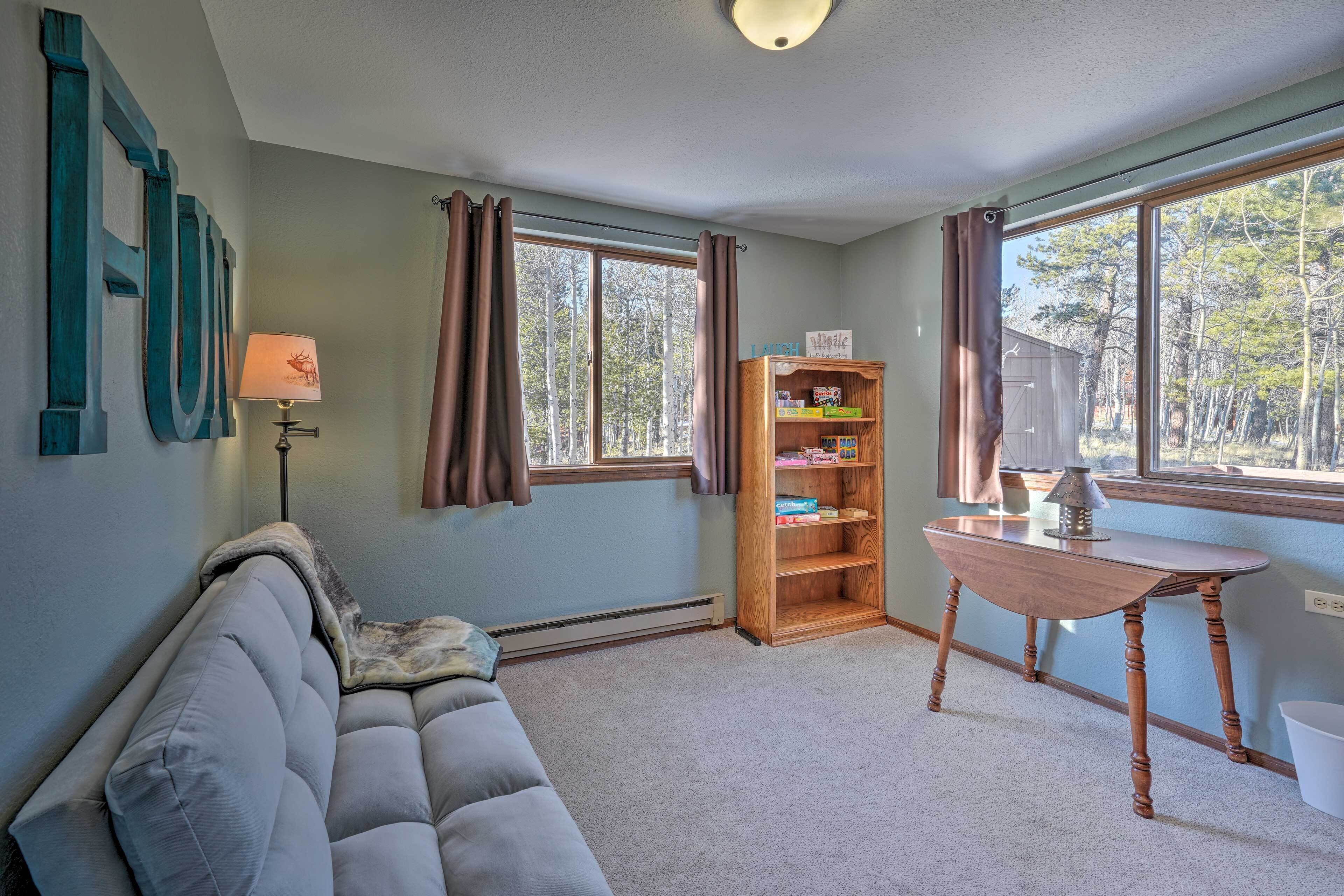 A cozy room with a grey sofa, a wooden table, and a bookshelf.