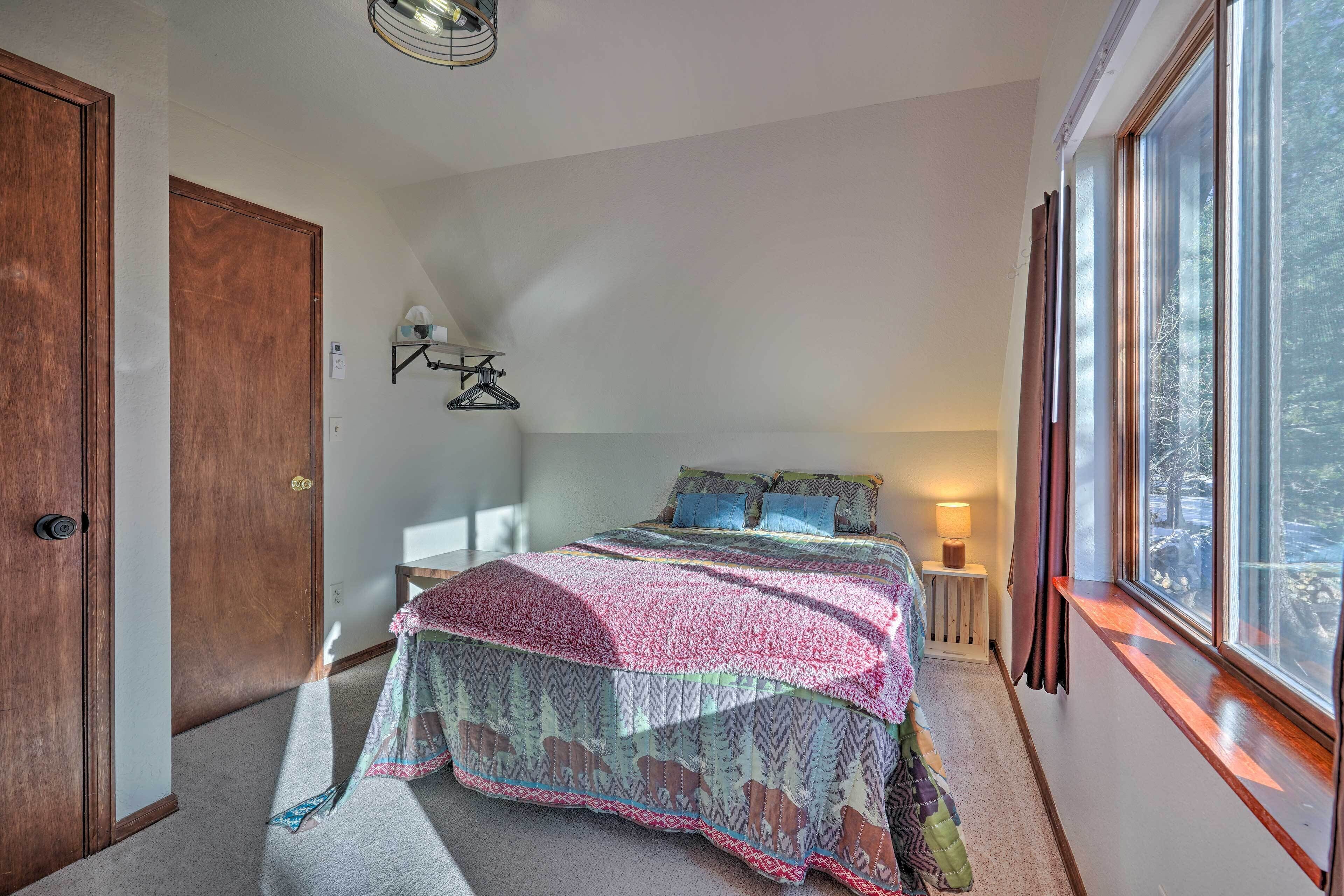 Une chambre à coucher avec un grand lit, une porte en bois, une fenêtre avec des rideaux et une lampe de chevet.