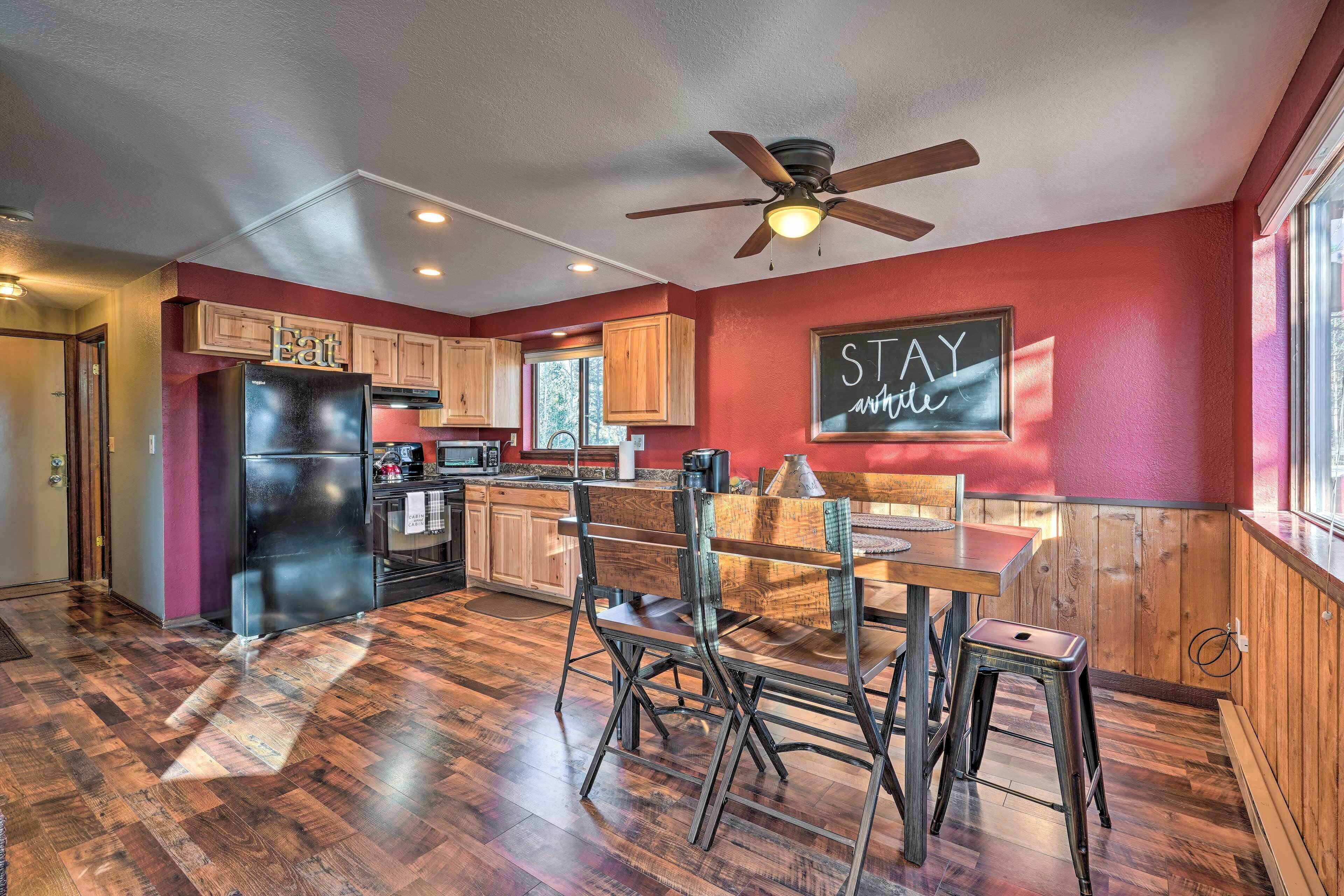 A spacious kitchen with wooden cabinets, a black refrigerator, and a dining area with stools.