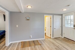 A room with light grey walls, a wooden floor, a white door, and a small rug. - Walk to Public Beach Access! Breezy Hampton Condo (Hampton)