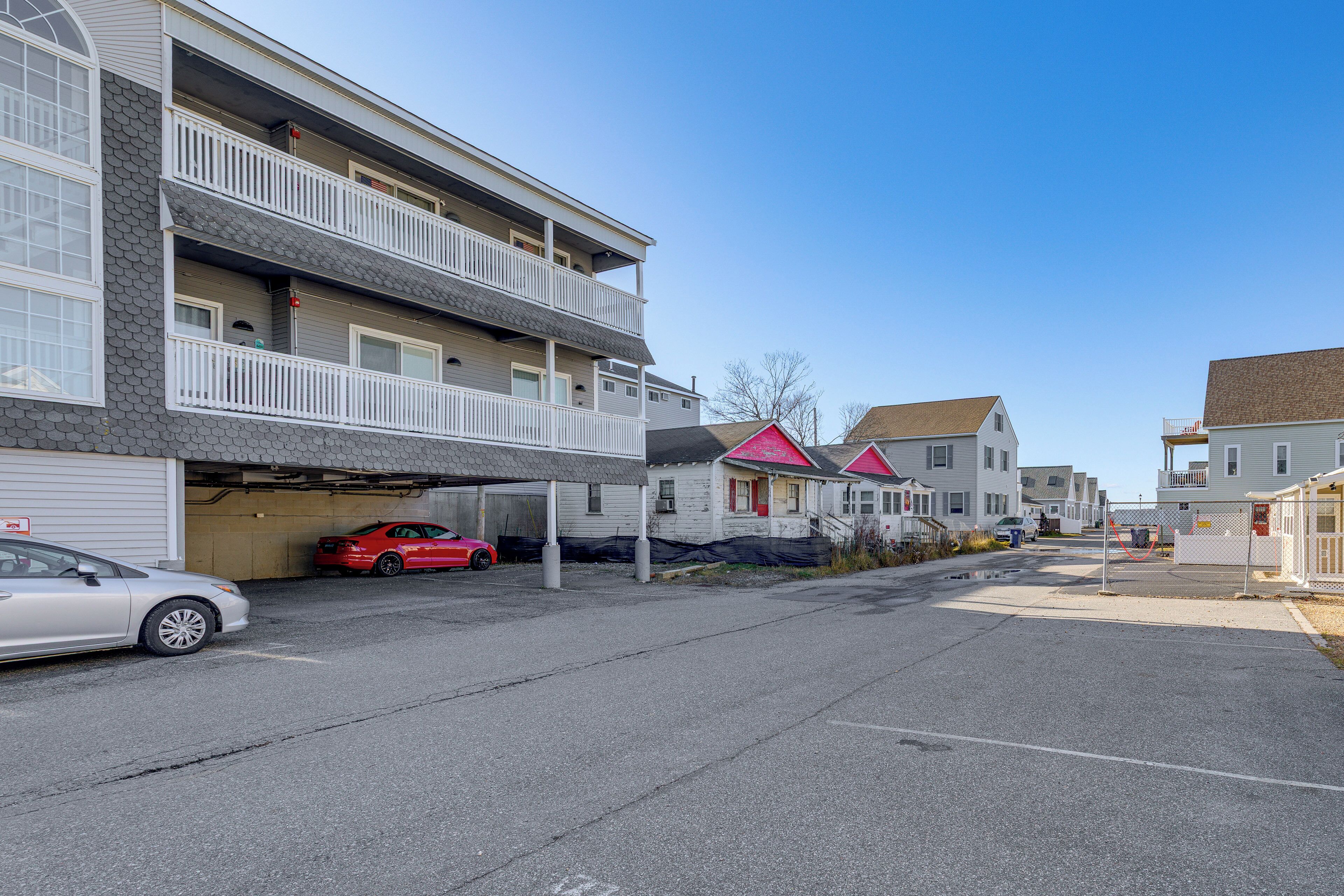 A multi-story residential building with a garage, a red car parked inside, and a clear blue sky.
