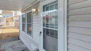 A house with a covered porch, a sliding glass door, and a small outdoor area with a stone pathway. - Walk to Public Beach Access! Breezy Hampton Condo (Hampton)