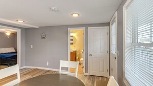 A compact living space with a dining area, a bedroom, and a bathroom visible through an open door. - Walk to Public Beach Access! Breezy Hampton Condo (Hampton)