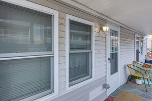 A house with large windows, a porch with chairs, and a door with a mailbox. - Walk to Public Beach Access! Breezy Hampton Condo (Hampton)