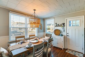 A dining area with a wooden table, chairs, and a hanging light fixture. - Tranquil Beach Haven in Family-friendly Brigantine (Brigantine)