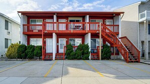 A multi-story building with a red exterior, multiple balconies, and a red staircase. - Steps to Sand & Surf! Couples Haven in Brigantine (Brigantine)