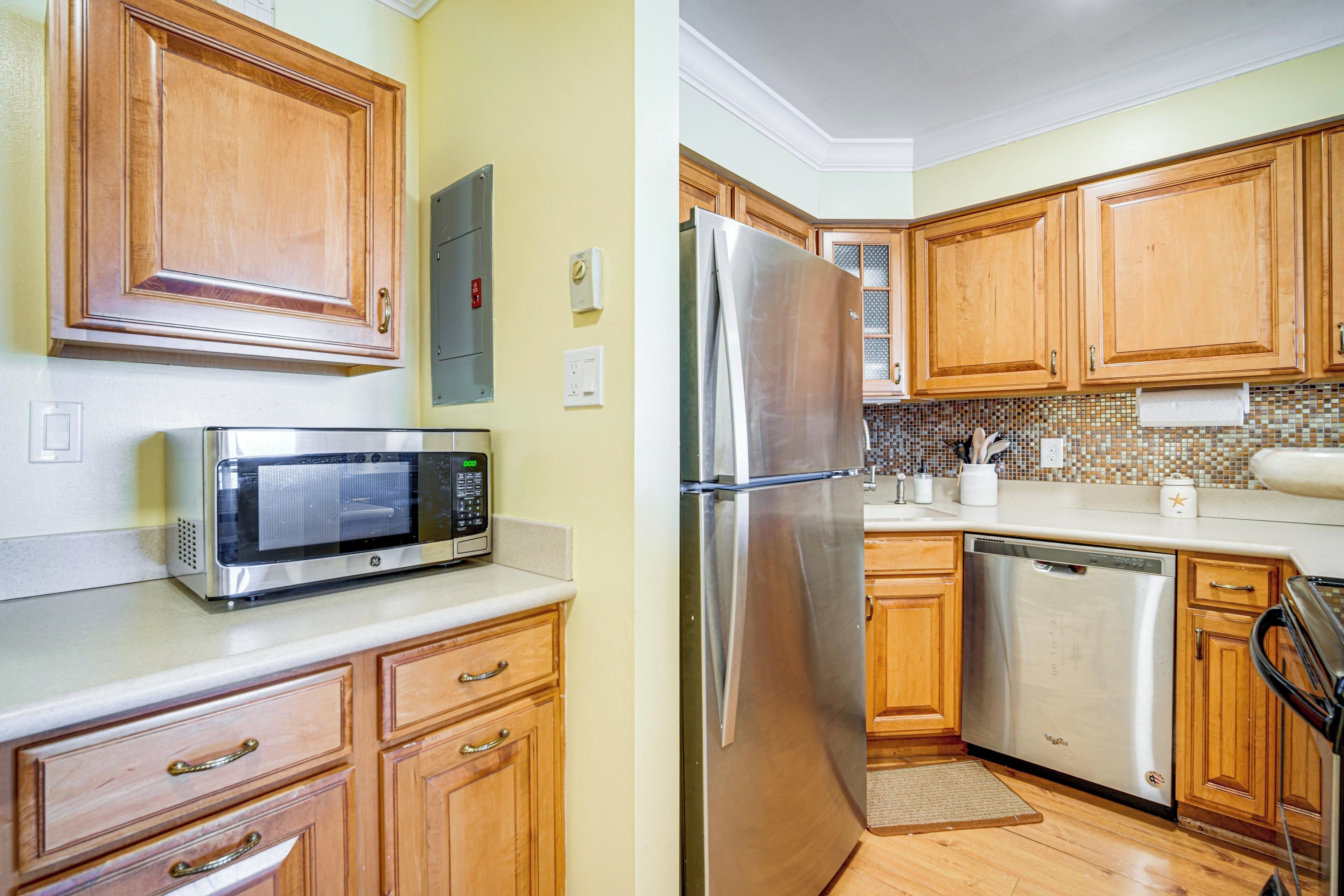 A kitchen with wooden cabinets, a stainless steel refrigerator, a microwave, and a dishwasher.