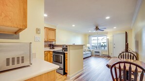 A modern kitchen with wooden cabinets, a built-in oven, and a dining area with a wooden table and chairs. - Steps to Sand & Surf! Couples Haven in Brigantine (Brigantine)