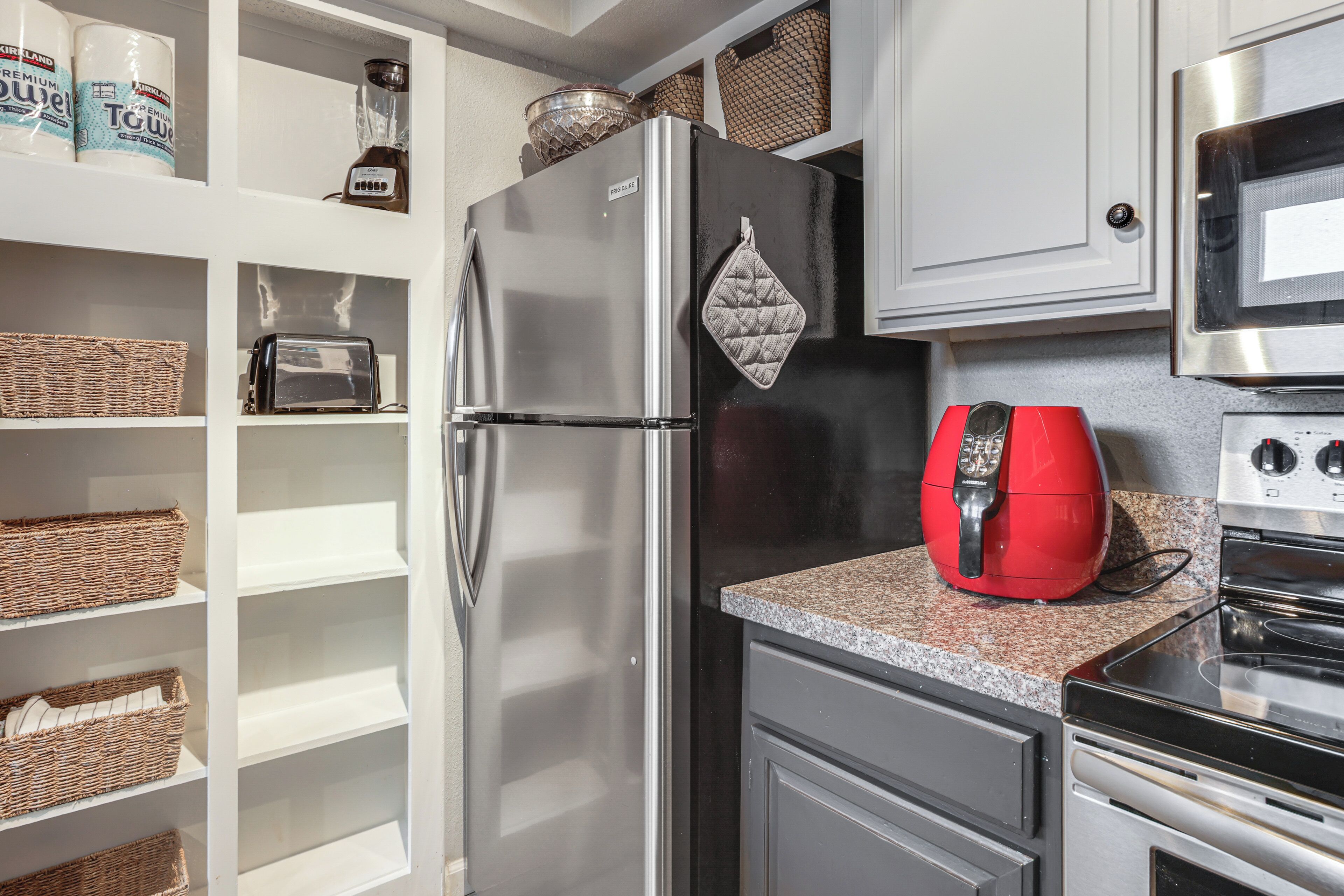 A kitchen with a stainless steel refrigerator, a microwave, and a red coffee maker on the counter.