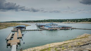 A waterfront dock area with a building, boats, and a pier. - Golf, Boat, Swim! Point Venture Retreat w/ Deck (Leander)