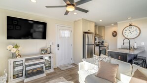 A modern living room with a flat-screen TV, a ceiling fan, and a kitchen area with a refrigerator and sink. - Walk to Marina: Waterfront South Holston Lake Home (Bristol)