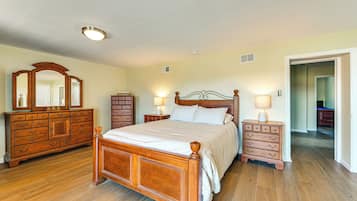 A bedroom with a wooden bed, two nightstands, a dresser, and a large mirror.