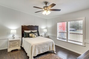 A bedroom with a bed, two bedside tables, a ceiling fan, and a window with blinds.