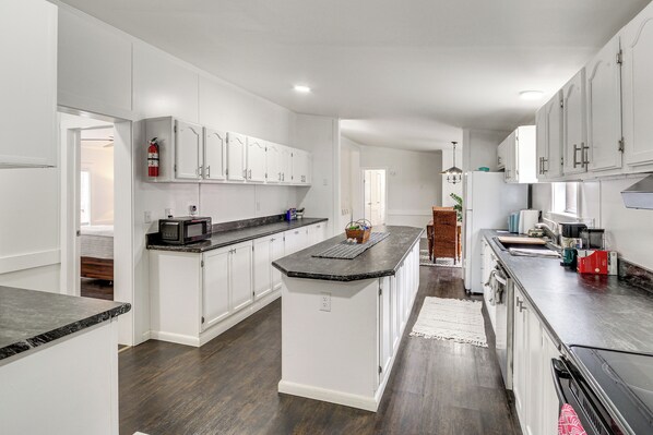 A modern kitchen with white cabinetry, a central island, and a microwave.