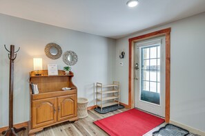 A wooden cabinet with a mirror, a welcome sign, and a red doormat at the entrance.