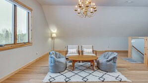 A spacious room with a large window, two chairs, a wooden table, and a chandelier. - Explore the Northeast Kingdom! Home w/ Deck (Norton)