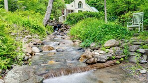 A house with a porch, surrounded by lush greenery and a stream. - Gorgeous Fall Foliage, Adjacent to Woodstock (Strafford)