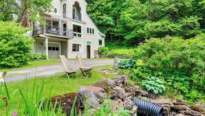 A two-story house with a balcony, surrounded by lush greenery and a garden. - Gorgeous Fall Foliage, Adjacent to Woodstock (Strafford)