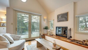 A spacious living room with a large window, a fireplace, a sofa, and a coffee table. - Gorgeous Fall Foliage, Adjacent to Woodstock (Strafford)