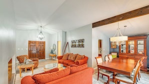 A spacious living room with a large orange sofa, a dining table with chairs, and a wooden cabinet. - Close to Hospitals & Downtown: Cleveland Home (North Olmsted)