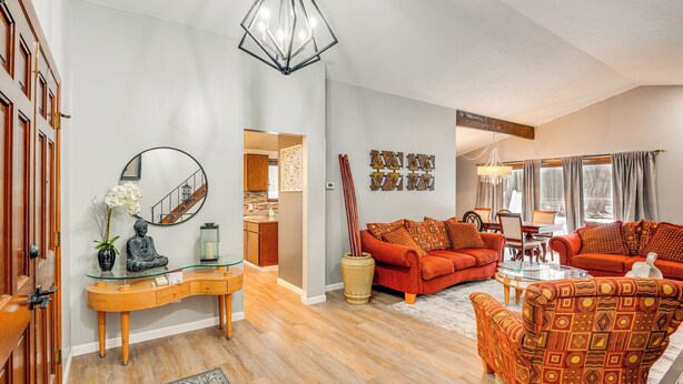 A living room with a sofa, armchair, and coffee table, wooden flooring, and a glass console table with decorative items. - Close to Hospitals & Downtown: Cleveland Home (North Olmsted)