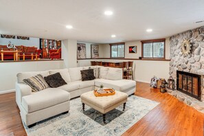 A living room with a sectional sofa, ottoman, and a stone fireplace. - Close to Hospitals & Downtown: Cleveland Home (North Olmsted)
