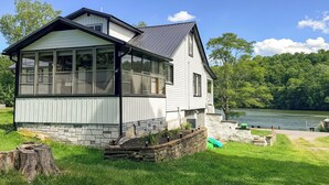 A two-story house with large windows, a stone foundation, and a view of a lake. - Year-round Fun on Lake Sheridan! Home w/ Patio (Nicholson)