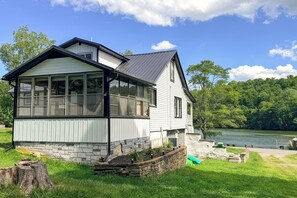 A two-story house with large windows, a stone foundation, and a view of a lake. - Year-round Fun on Lake Sheridan! Home w/ Patio (Nicholson)