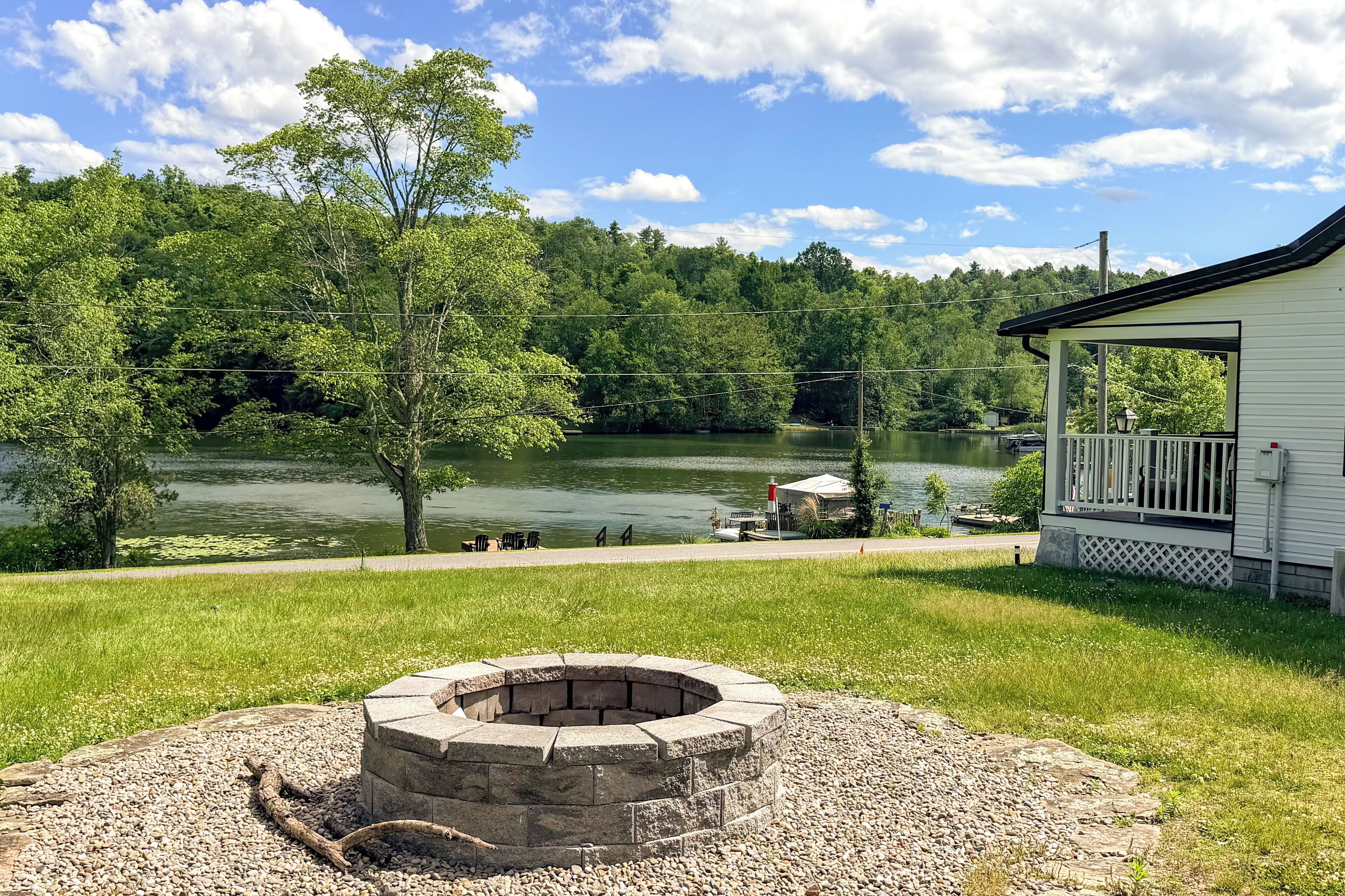 A lakeside cabin with a fire pit, a dock, and a grassy area.