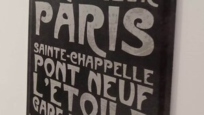 En svart metallskylt med vit text som listar sevärdheter i Paris.