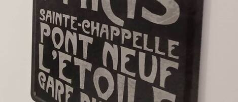 A black metal sign with white text listing Paris attractions.