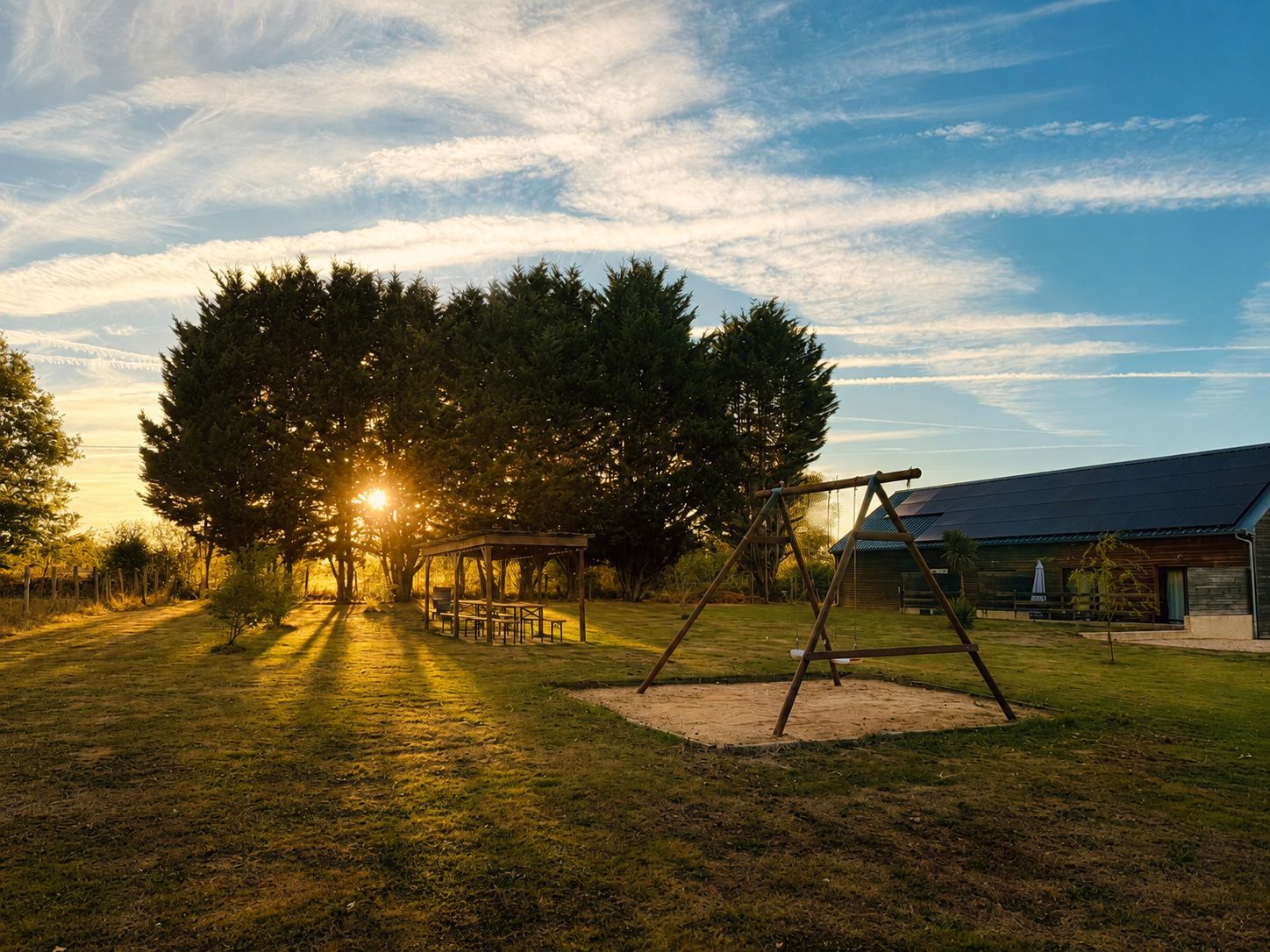 A park with a swing set, picnic tables, and a building in the background.