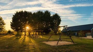 A park with a swing set, picnic tables, and a building in the background.
