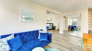 A modern living room with a blue sofa, a round coffee table, and a wooden floor. - Snead Island Getaway! Steps to Bay & Emerson Point (Palmetto)