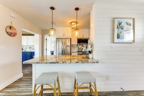 A kitchen with white cabinets, a granite countertop, and two bar stools. - Snead Island Getaway! Steps to Bay & Emerson Point (Palmetto)