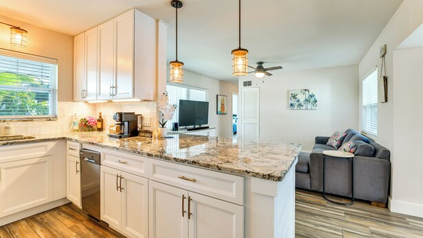 A modern kitchen with white cabinets, granite countertops, and pendant lighting. - Snead Island Getaway! Steps to Bay & Emerson Point (Palmetto)