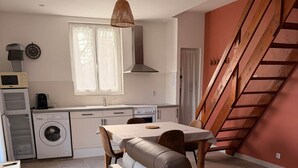 Ein kompakter Wohnraum mit Essbereich, einer Couch, einer Waschmaschine und einer Treppe.