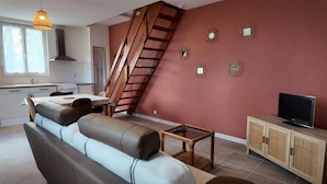 Ein modernes Wohnzimmer mit einer Couch, einem Fernseher, einem Holzschrank und einer Treppe.