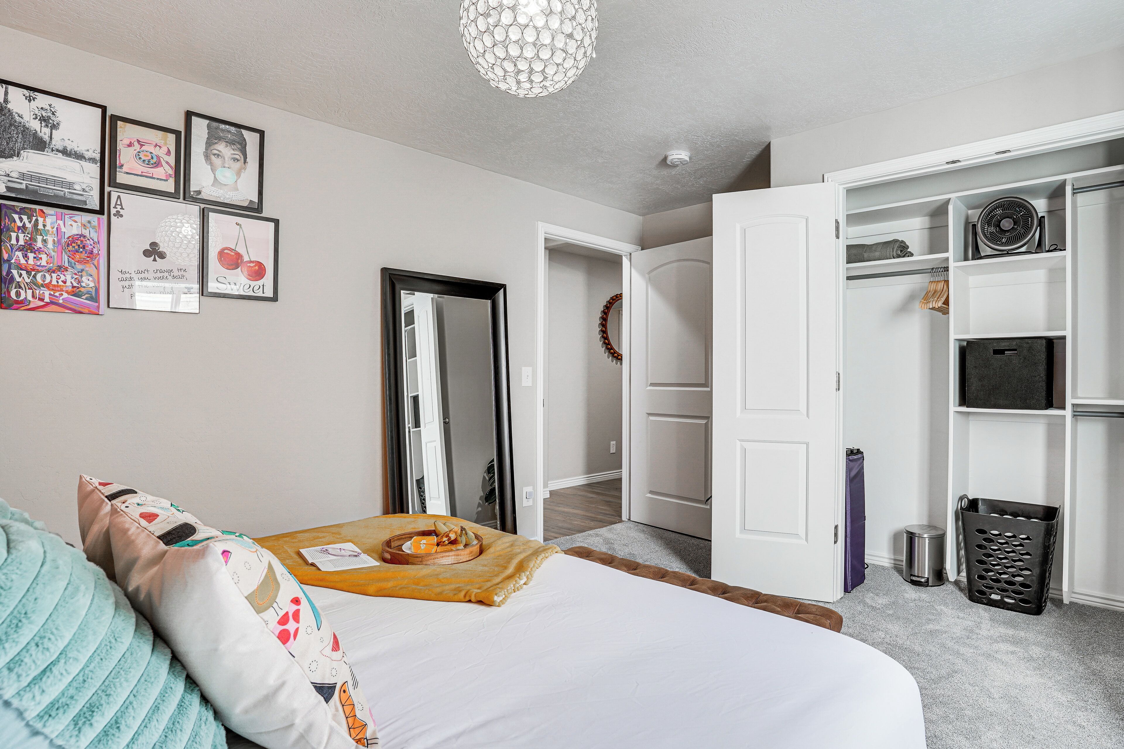 A bedroom with a bed, a bedside table with a tray, a wardrobe, and a mirror.