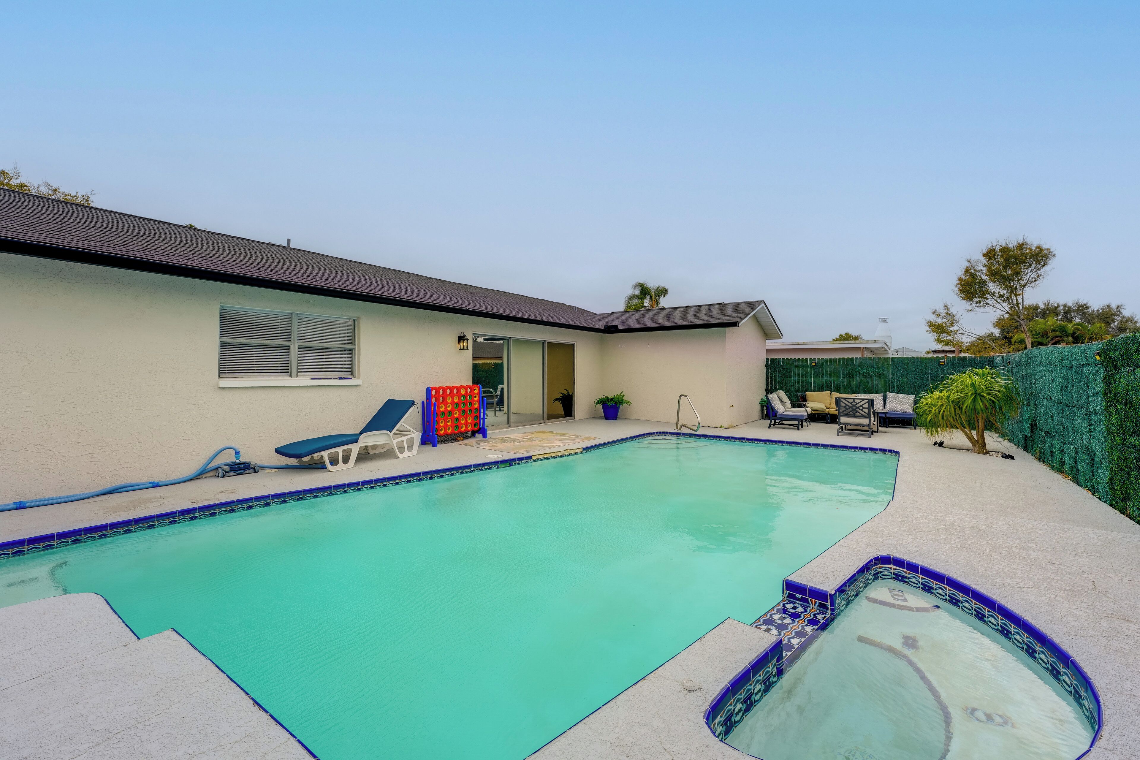 A swimming pool with a tiled edge, a covered patio area, and a small hot tub.