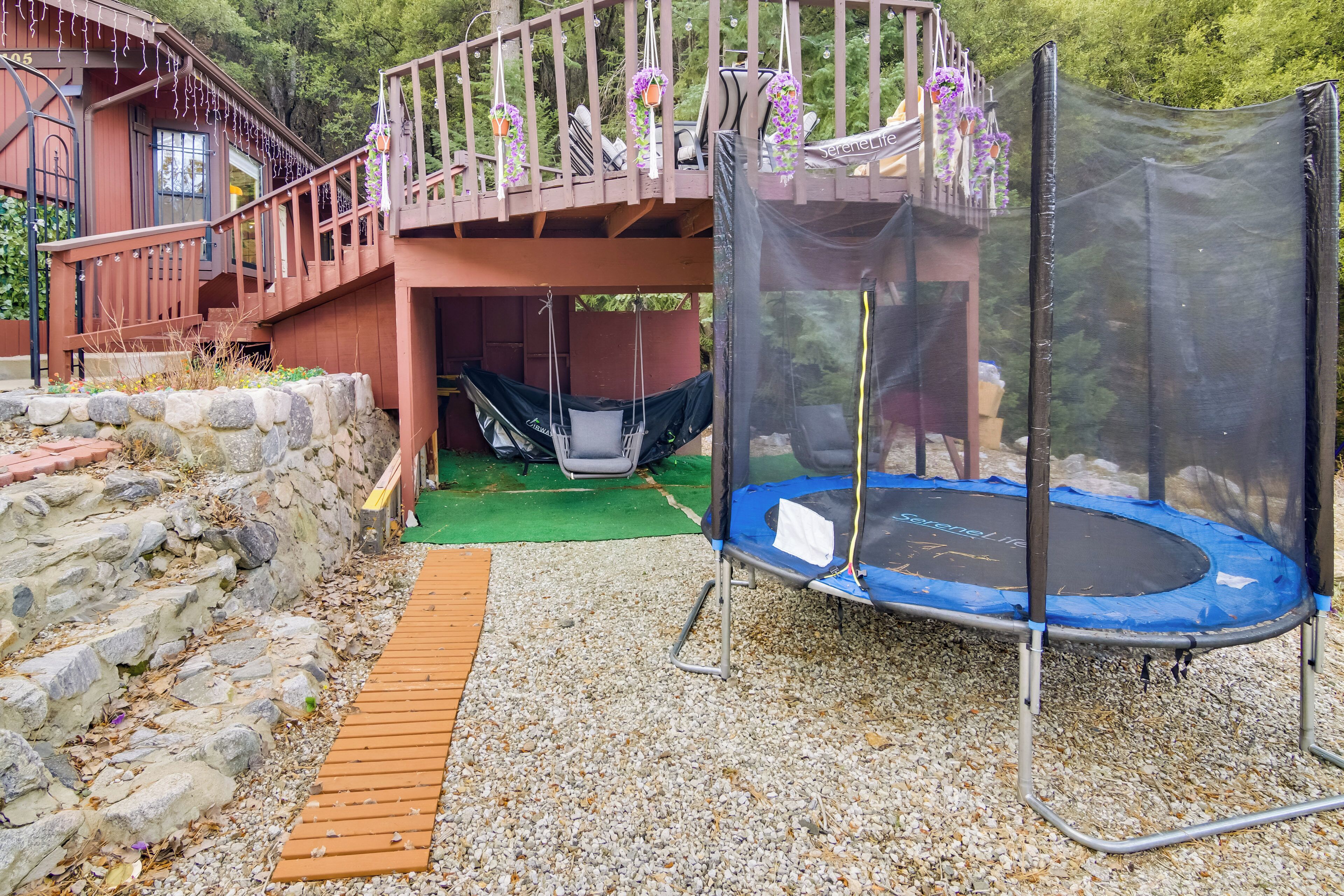 A wooden deck with a trampoline and a covered seating area.