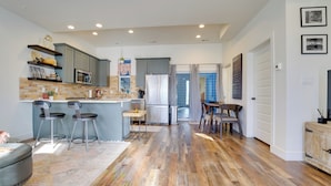 Una cocina moderna con una isla central, taburetes de bar y un comedor con mesa y sillas.