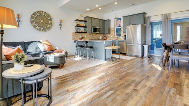 Una sala de estar moderna con un sofá gris, una mesa de centro redonda y una zona de comedor con una mesa de madera y sillas.