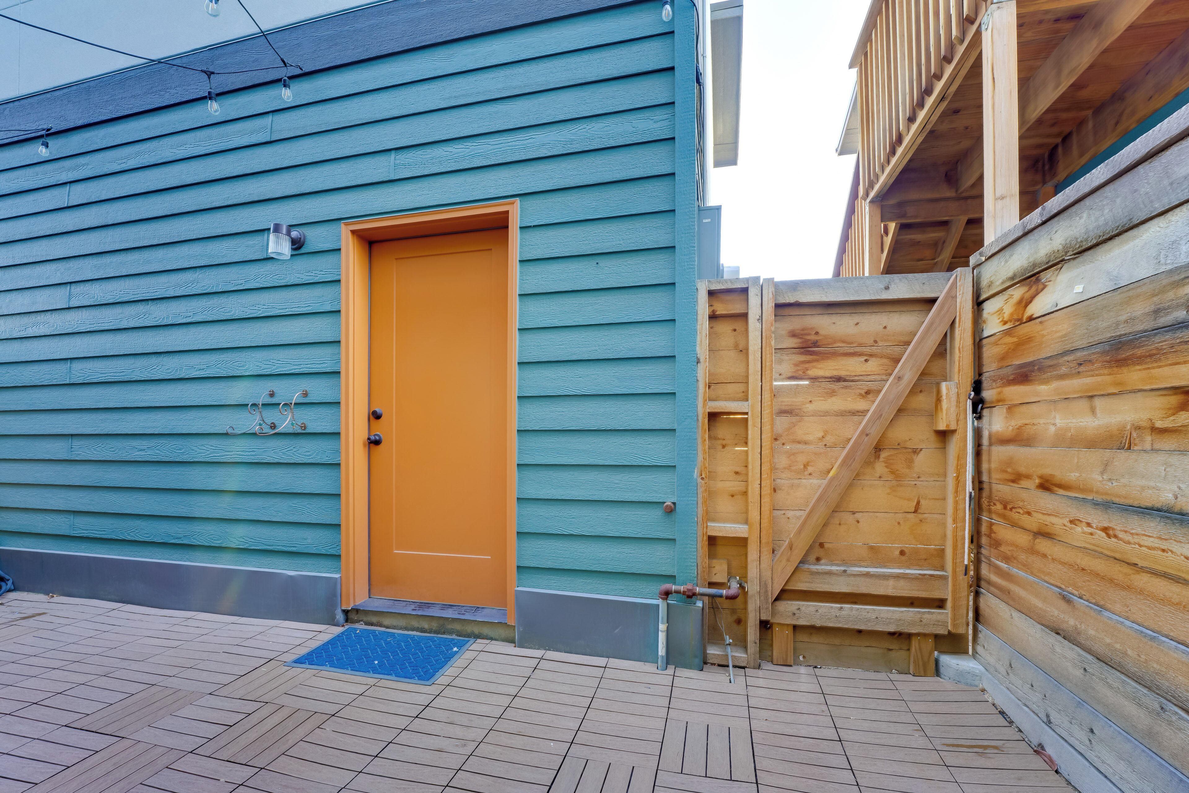 A wooden house with a blue exterior and an orange door.