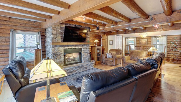 A log cabin interior with a stone fireplace, leather seating, and wooden beams. - Hike, Fish & Boat Nearby! Bloomington Family Cabin (Bloomington)