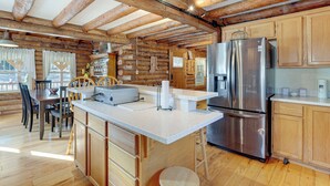 A log cabin-style kitchen with wooden beams, a stainless steel refrigerator, and a dining area with a table and chairs. - Hike, Fish & Boat Nearby! Bloomington Family Cabin (Bloomington)