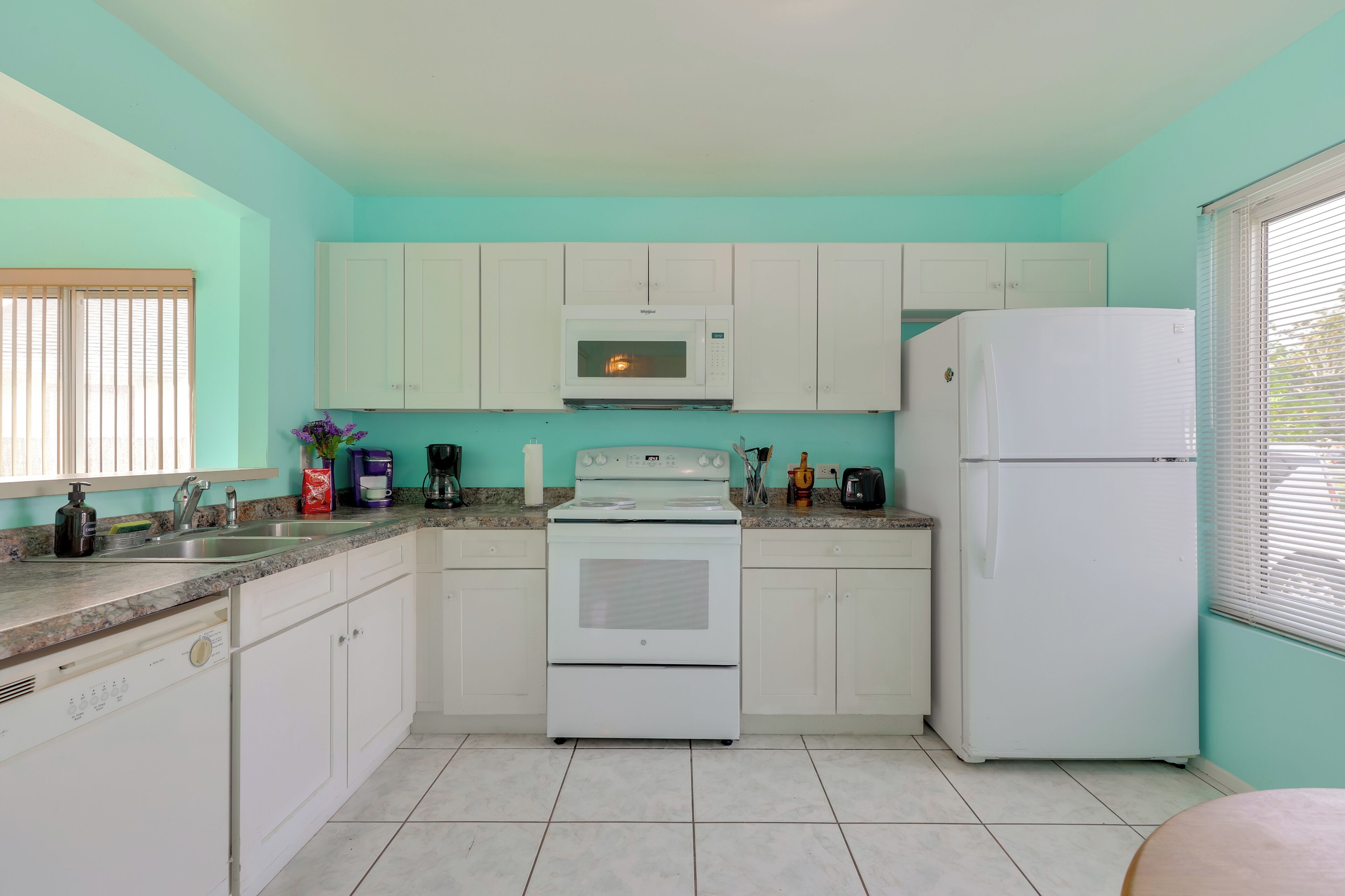 A kitchen with white cabinets, a microwave, a stove, and a refrigerator.