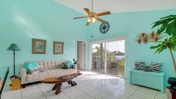 A living room with a white sofa, a wooden coffee table, and a ceiling fan.
