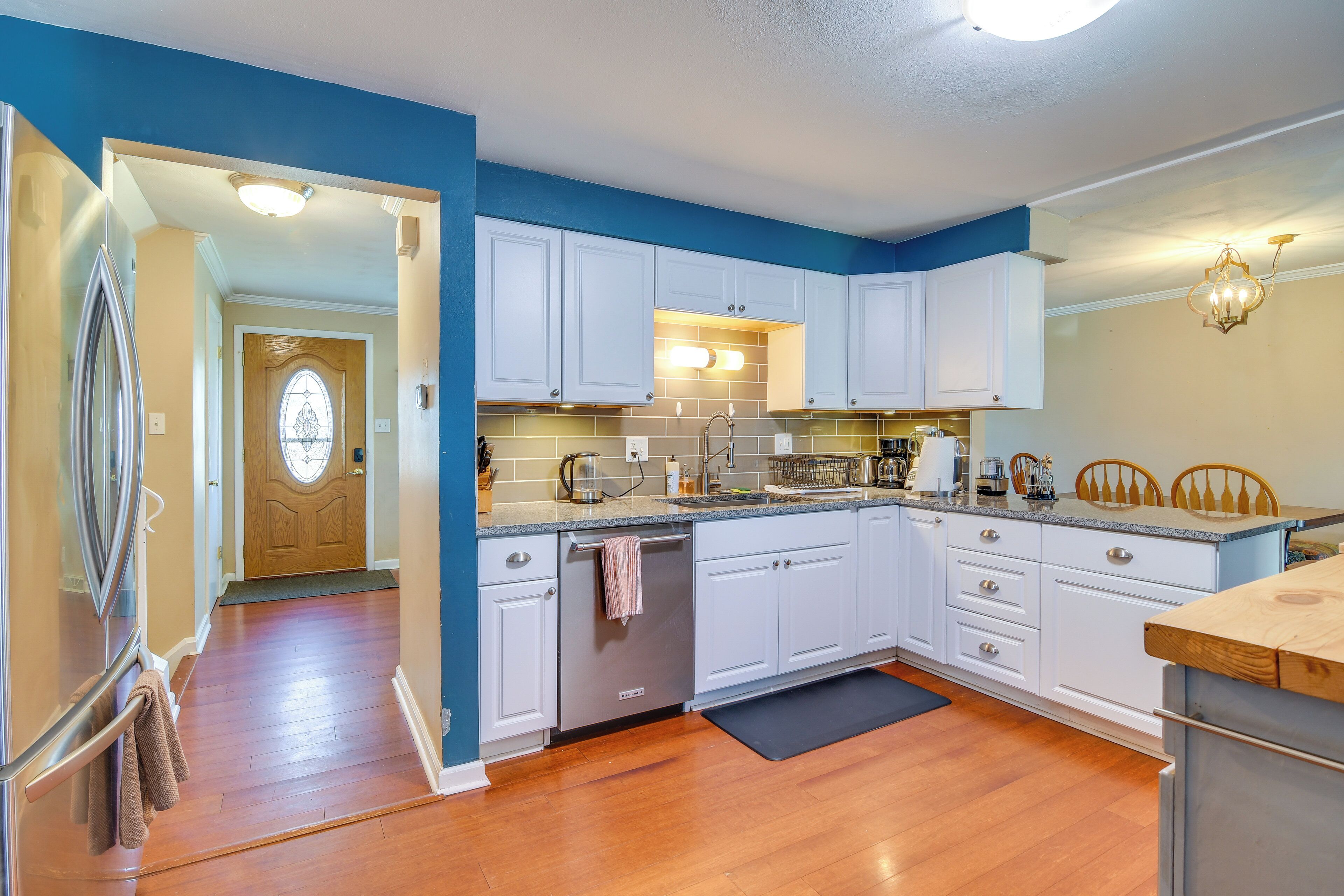 A kitchen with white cabinets, a wooden countertop, and a black rug.