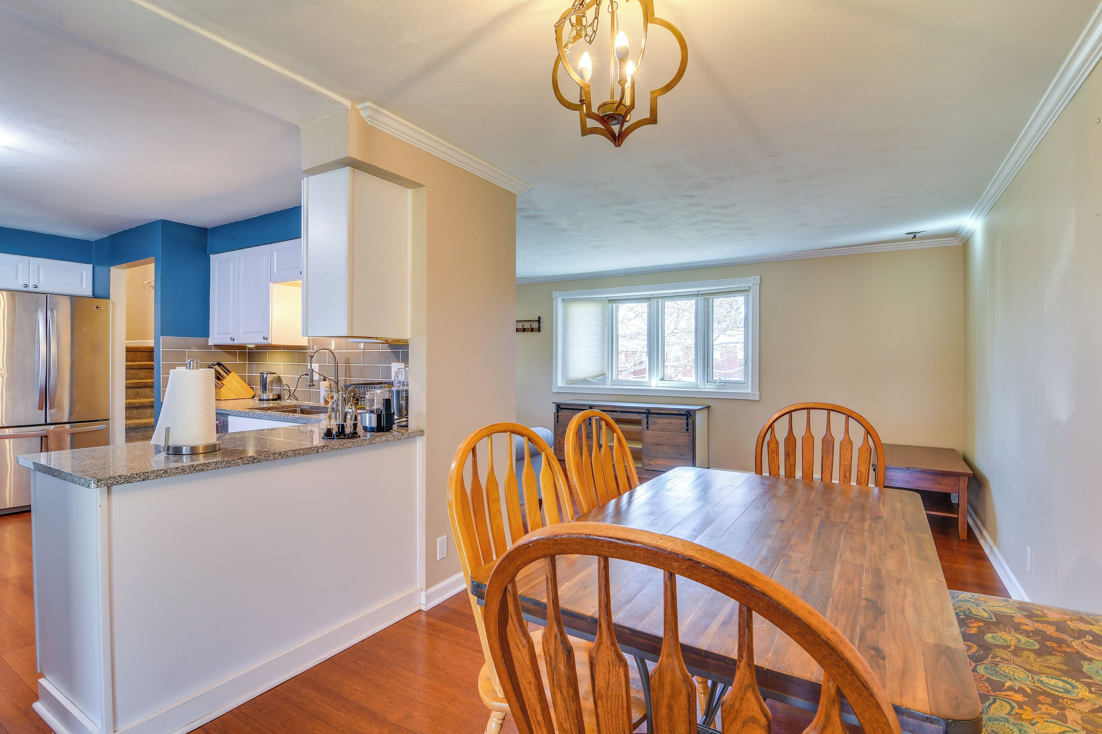 A modern kitchen with a central island, wooden chairs, and a dining table.